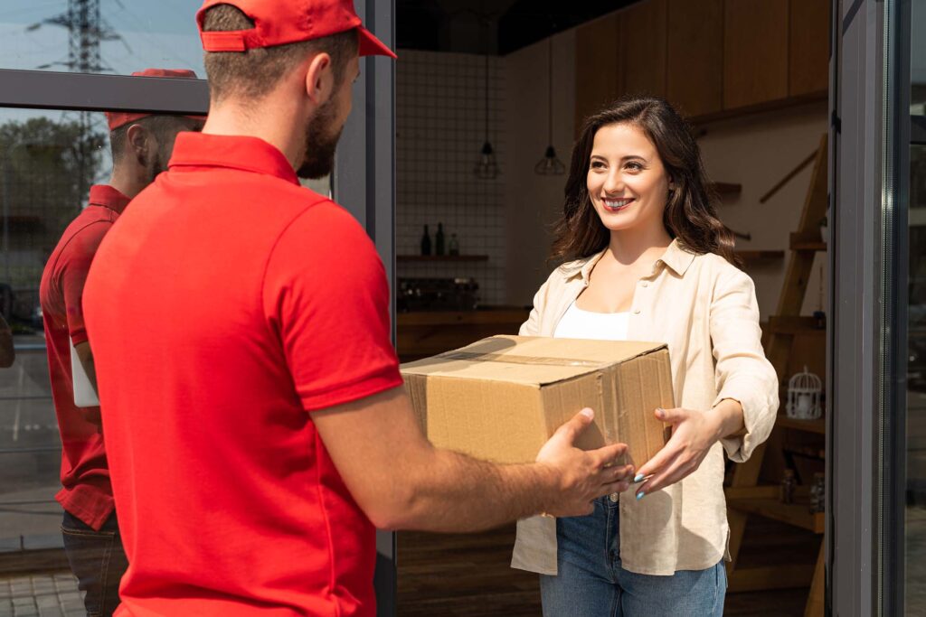delivery-man-giving-cardboard-box-to-happy-woman-DVE454J.jpg