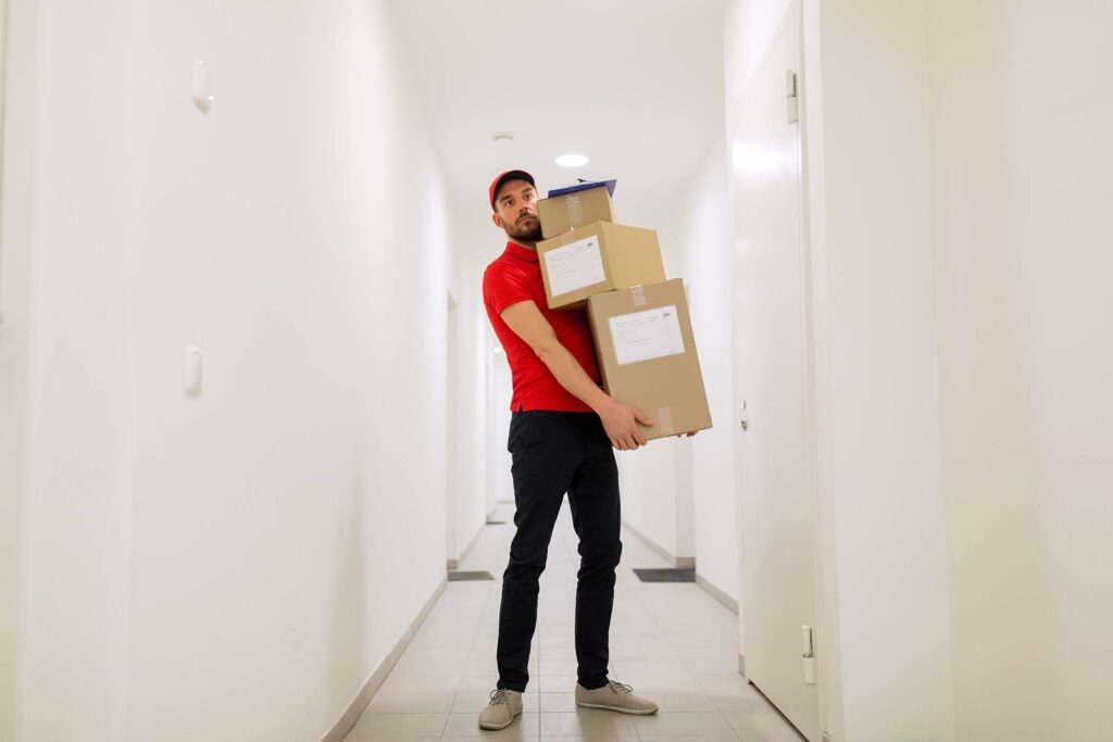 delivery-man-with-parcel-boxes-in-corridor-PF8FFFB.jpg