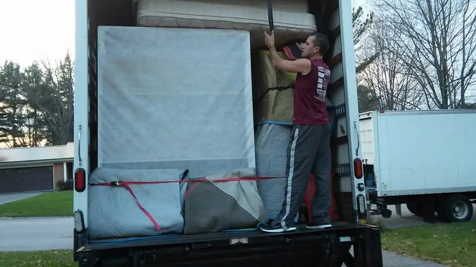 Mover loading a wrapped mattress into a moving truck