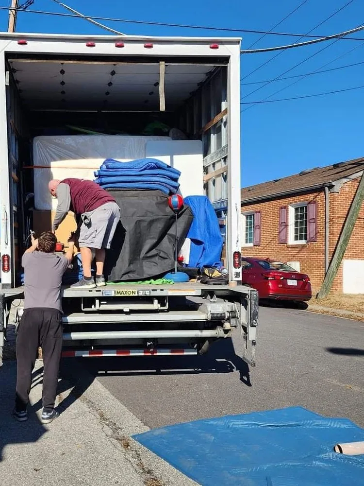 Collegiate Movers crew loading furniture onto a truck lift gate